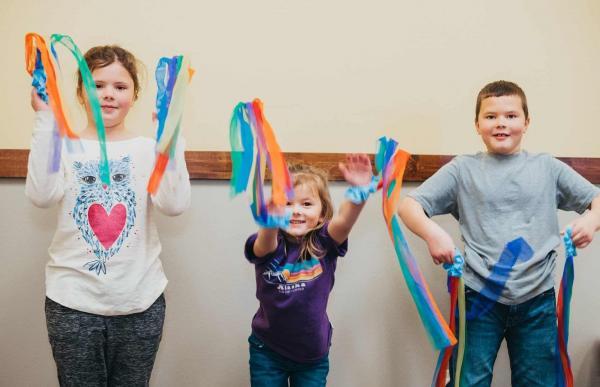 Boy Reads On Couch In Front Of Rainbow Streamers by Stocksy